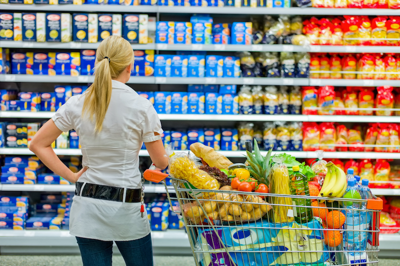 A picture of a lady looking at a the possible food selections at a grocery store