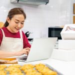 smiling women using laptop in kitchen