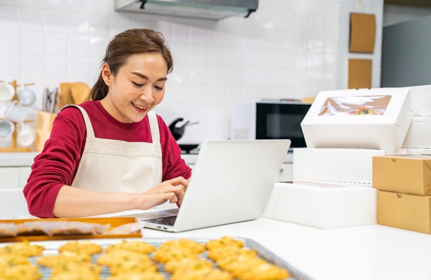 smiling women using laptop in kitchen